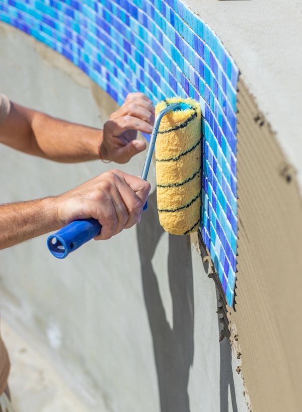 A man lays mosaic tiles in a swimming pool. Selective focus.